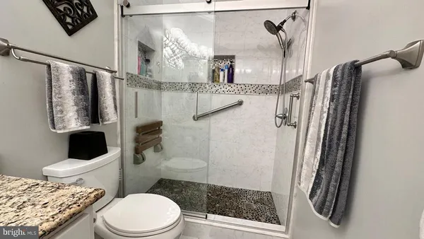 a bathroom with a granite countertop sink a mirror and a shower