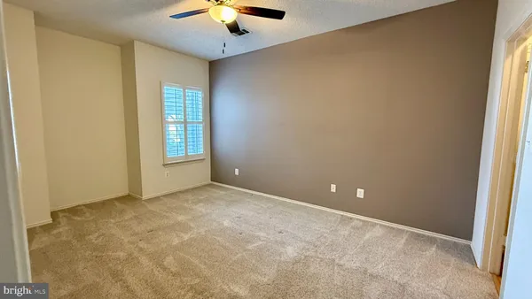an empty room with windows and chandelier fan