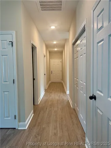 an empty room with wooden floor chandelier fan and windows