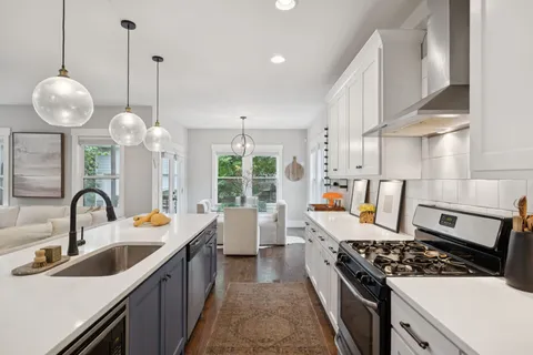 a kitchen with stove a sink a counter space and living room view