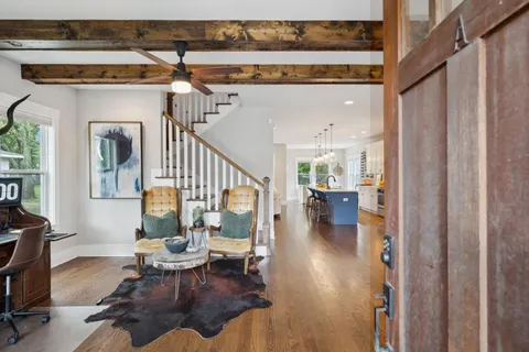 a living room with furniture and a dining table with wooden floor
