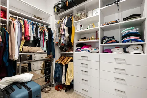a view of walk in closet with clothes and shoes
