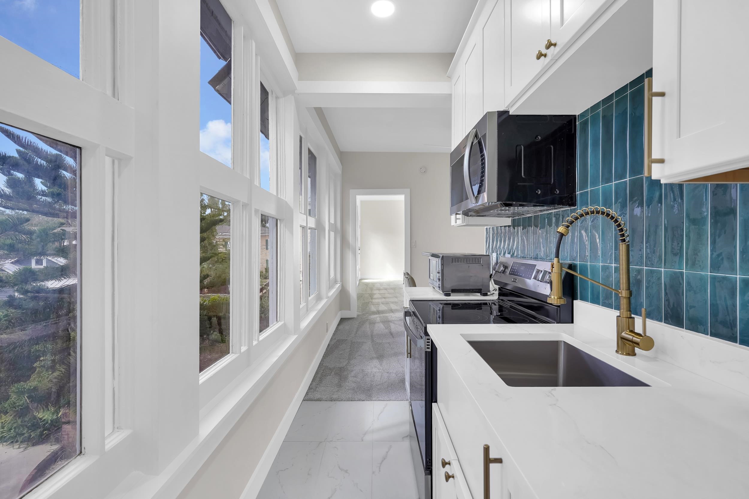 268 St George Street St. Augustine, FL 32084 - Photo 49 of 71 Kitchen with white cabinetry, range with electric stovetop, light stone countertops, stainless steel microwave, and light marble finish floors