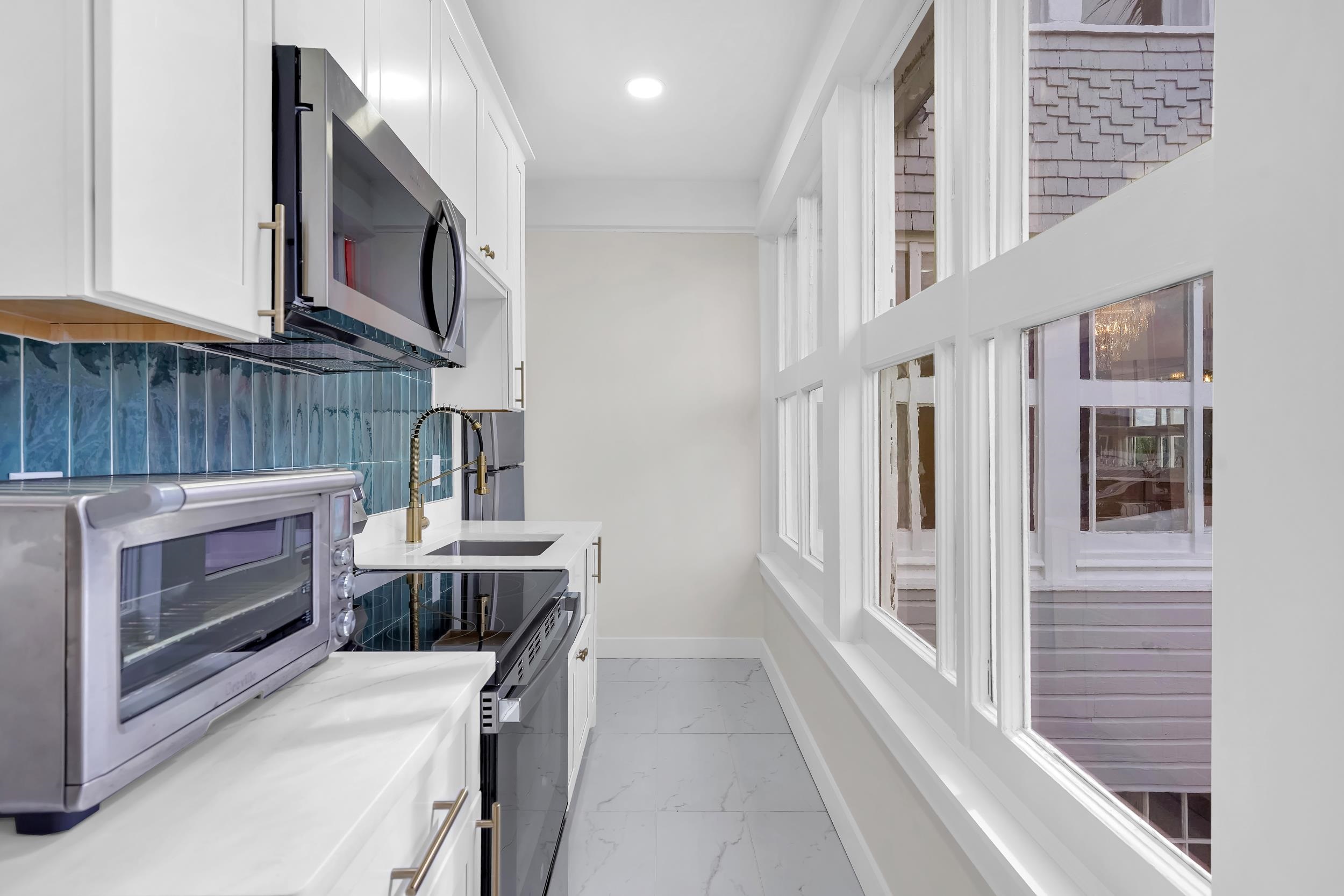 268 St George Street St. Augustine, FL 32084 - Photo 52 of 71 Kitchen featuring white cabinets, stainless steel microwave, light marble finish floors, decorative backsplash, and recessed lighting