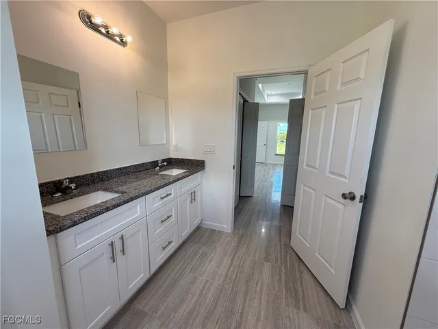 a bathroom with a granite countertop double vanity sink and mirror