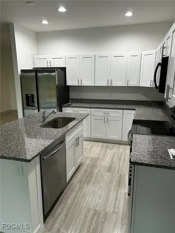 a kitchen with granite countertop a sink a stove and cabinets