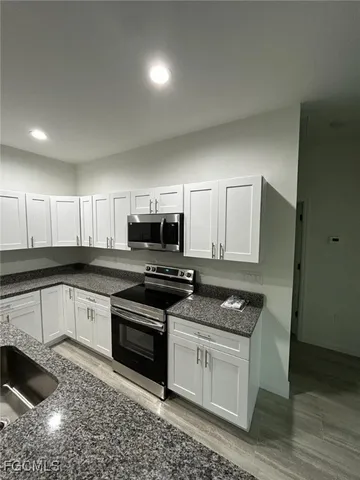 a kitchen with stainless steel appliances granite countertop a stove a sink and a microwave