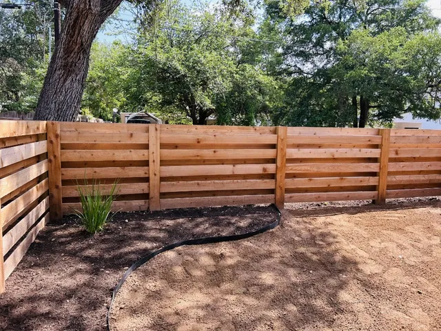 a view of backyard with wooden fence and a large tree