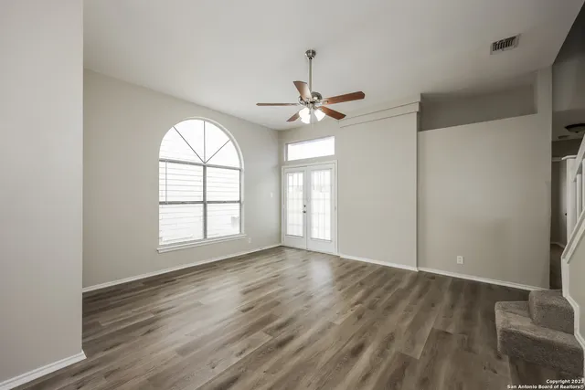 a view of an empty room with a window and wooden floor