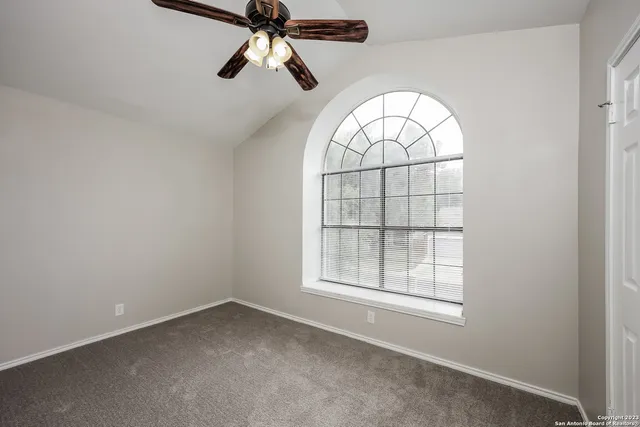 an empty room with windows and fan