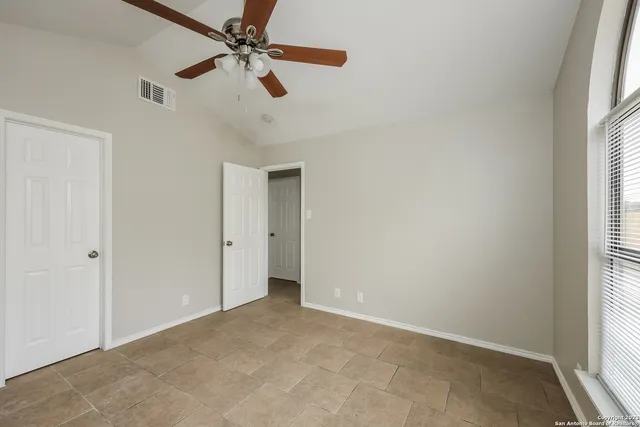 an empty room with windows and fan
