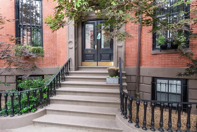 a view of a brick house with many windows and plants