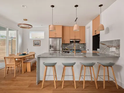 a kitchen with stainless steel appliances kitchen island granite countertop a dining table chairs and white cabinets