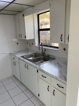 a kitchen with granite countertop white cabinets and a sink