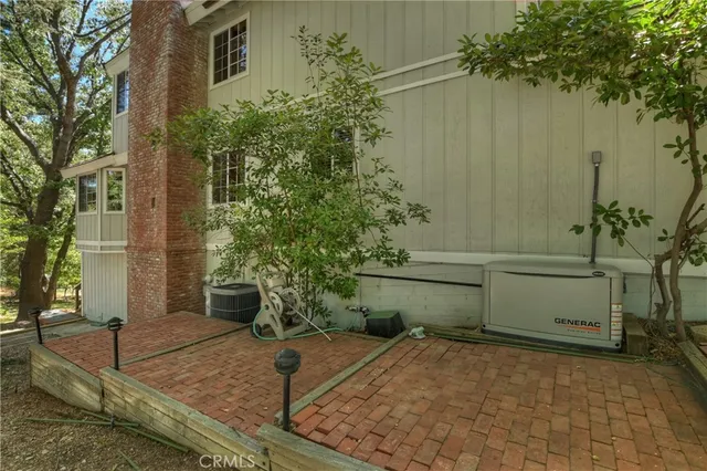 a view of a brick house next to a yard with large trees