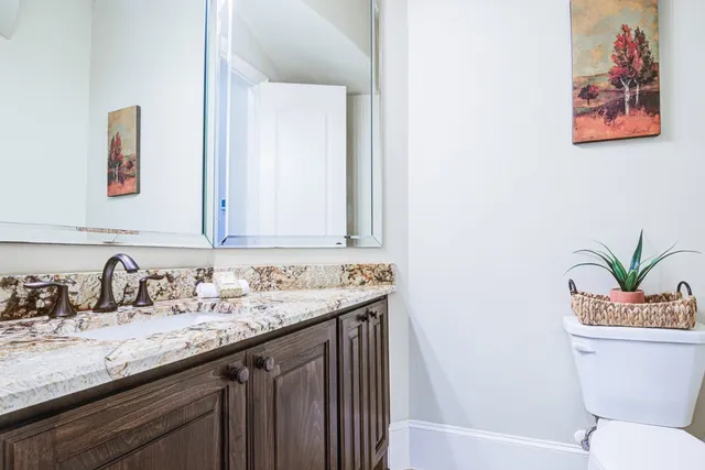 a bathroom with a granite countertop sink a toilet and a mirror