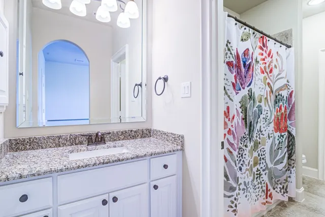 a bathroom with a granite countertop sink a mirror and shower curtain