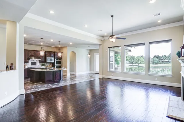 a view of a kitchen and an empty room with wooden floor and a window