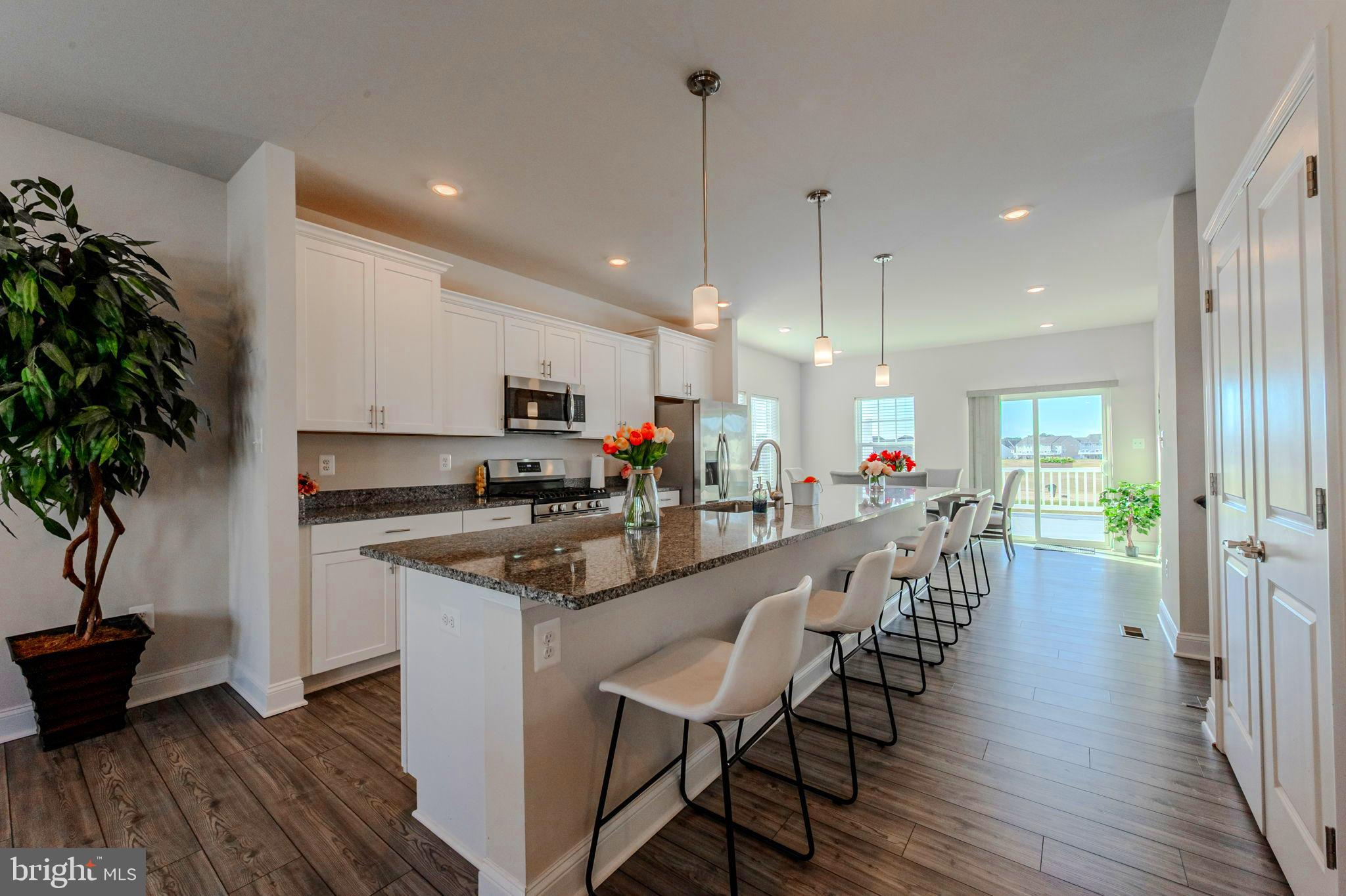 35262 Wright Way Millsboro, DE 19966 - Photo 5 of 42 a kitchen with stainless steel appliances a dining table chairs stove and white cabinets