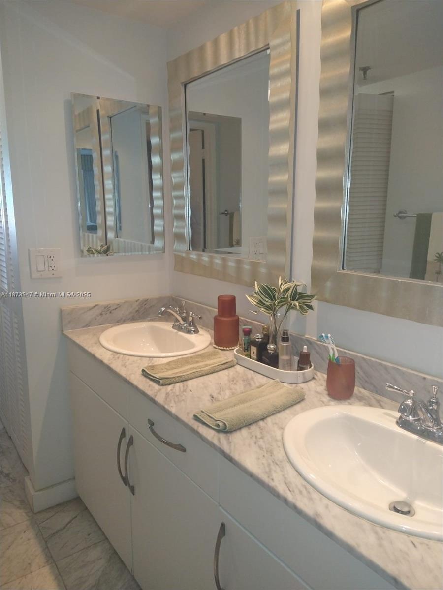 9341 Collins Avenue, Unit 806 Surfside, FL 33154 - Photo 13 of 27 a bathroom with double vanity sinks and a mirror