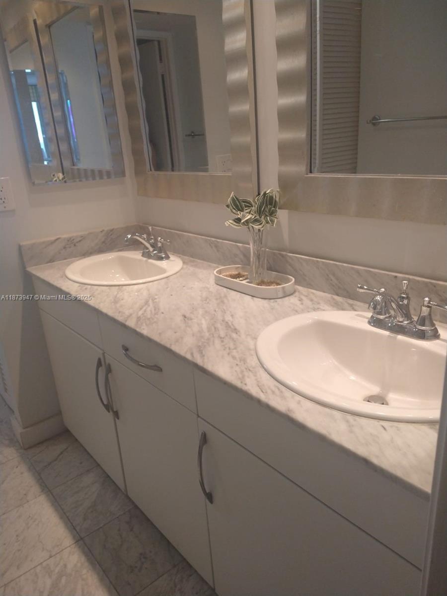 9341 Collins Avenue, Unit 806 Surfside, FL 33154 - Photo 24 of 27 a bathroom with double sink and a mirror