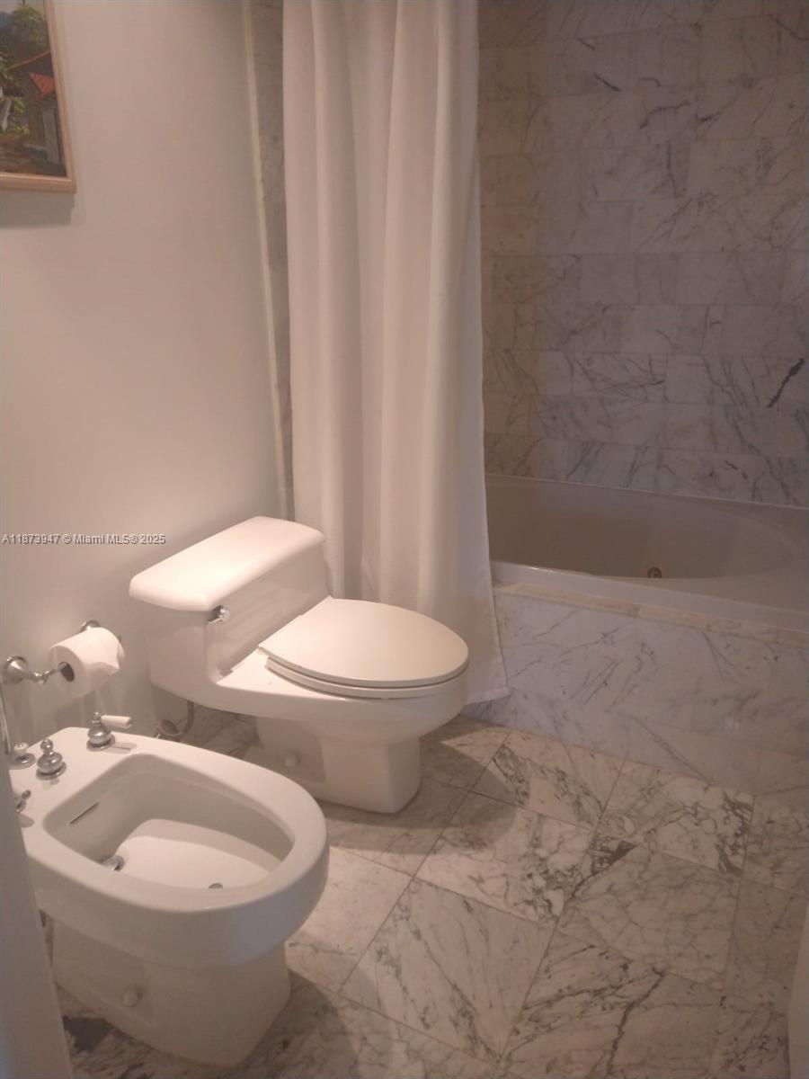 9341 Collins Avenue, Unit 806 Surfside, FL 33154 - Photo 25 of 27 a white toilet sitting next to a shower curtain