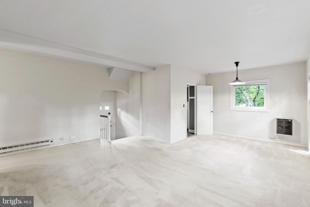 an empty room with chandelier fan and windows