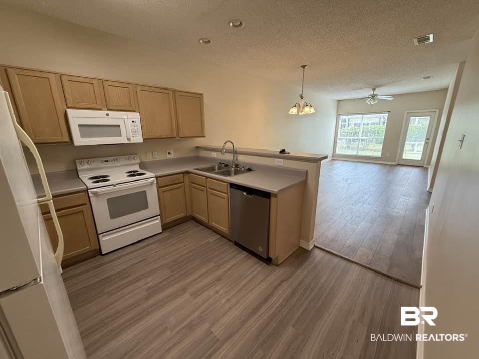 2651 South Juniper Street, Unit 401 Foley, AL 36535 - Photo 12 of 27 Kitchen with a sink, visible vents, a peninsula, white appliances, and a textured ceiling