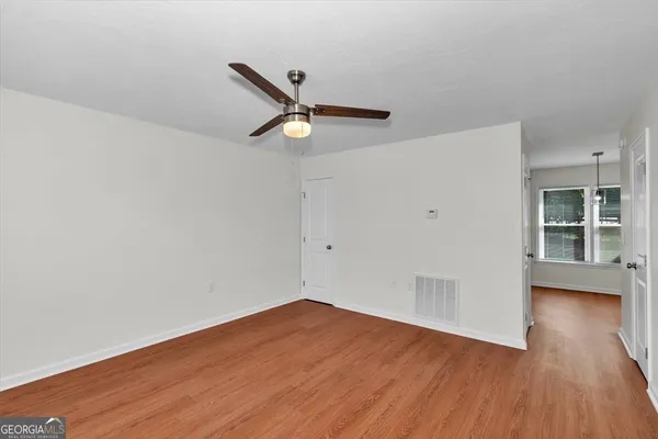 a view of a big room with wooden floor and windows