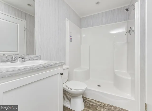 a bathroom with a granite countertop sink a toilet and shower