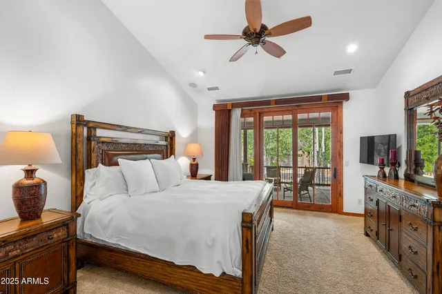 a bedroom with a large bed a flat tv screen and a dresser