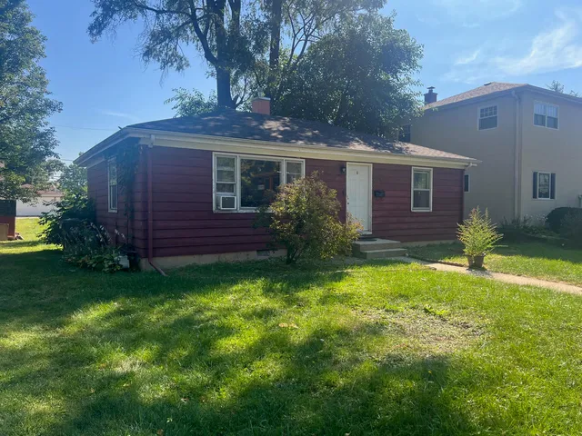 a view of a yard in front of a house with plants and large tree