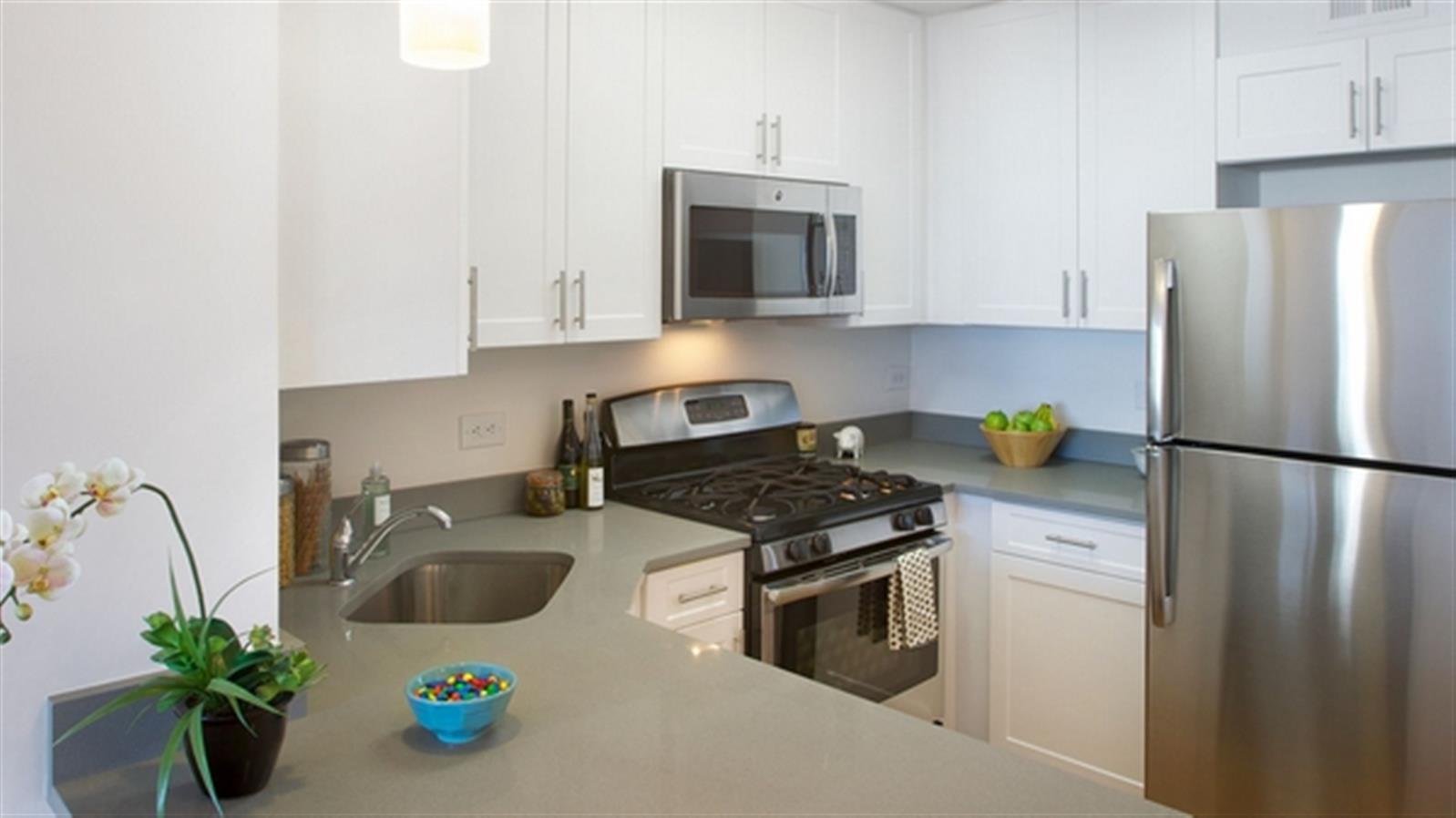 a kitchen with stainless steel appliances a stove a sink a refrigerator a microwave a counter space and cabinets