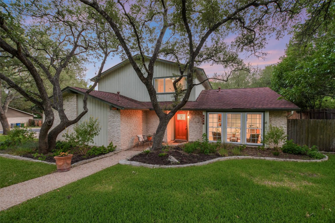 a view of a house with a yard and a large tree