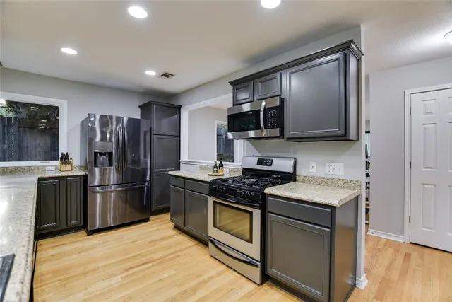 a kitchen with stainless steel appliances granite countertop a stove top oven a refrigerator and a sink