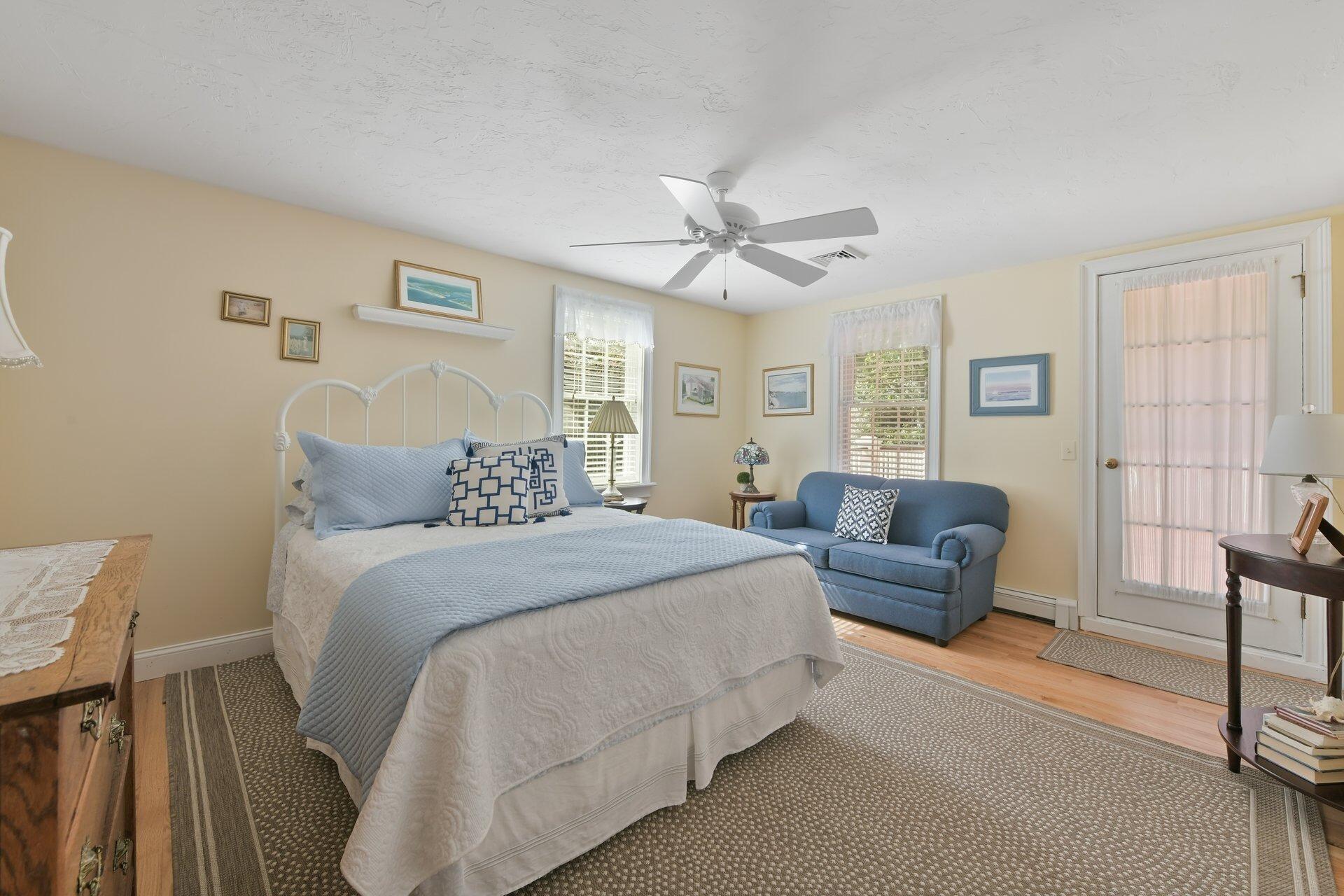 65 Tracey Road Cotuit, MA 02635 - Photo 19 of 36 a spacious bedroom with a bed a couch and a chandelier