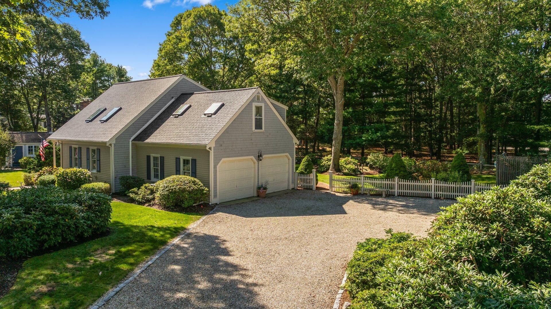 65 Tracey Road Cotuit, MA 02635 - Photo 2 of 36 a front view of a house with a yard table and chairs