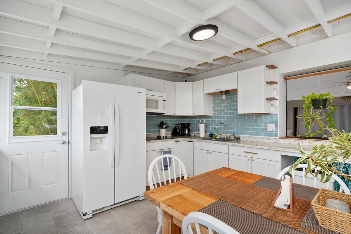 85-4563 Hawaii Belt Road Captain Cook, HI 96704 - Photo 22 of 30 a kitchen with stainless steel appliances a refrigerator a sink a stove a dining table and chairs