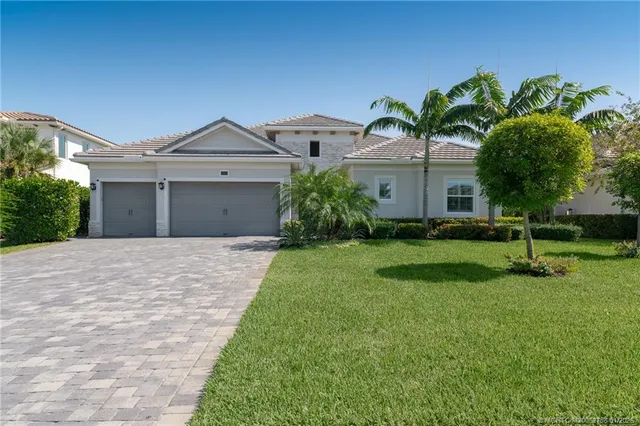 a front view of a house with a yard and palm trees
