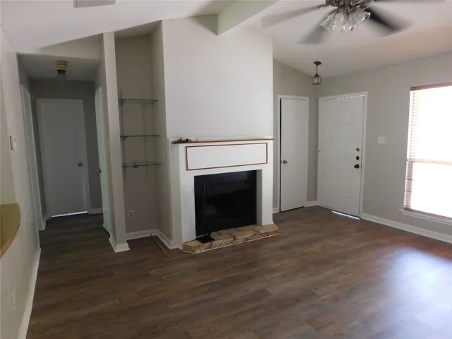 an empty room with wooden floor a fireplace and windows