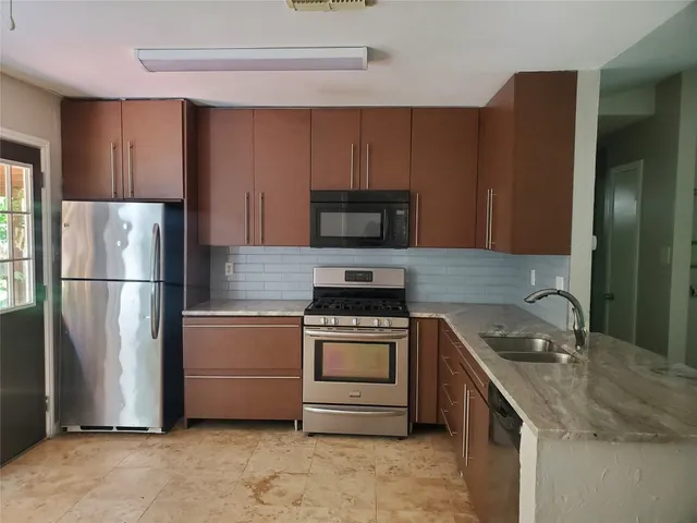 a kitchen with granite countertop a refrigerator stove and microwave