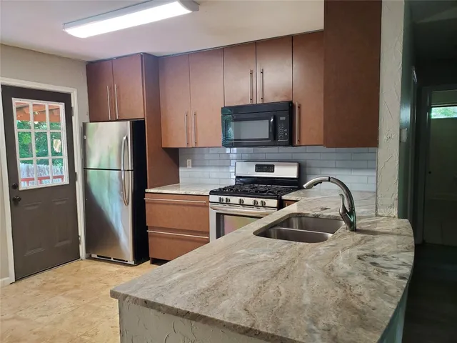 a kitchen with granite countertop a refrigerator stove and microwave