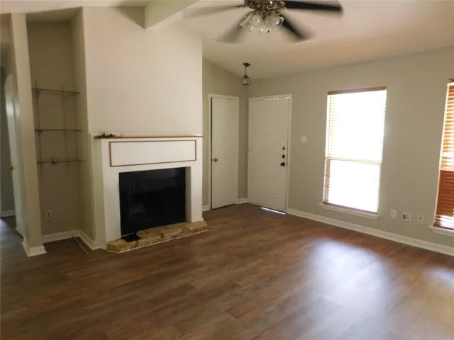an empty room with wooden floor a fireplace and windows