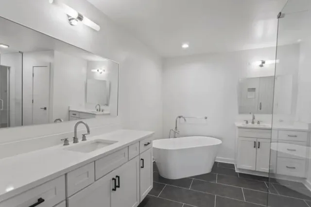 a bathroom with a double vanity sink mirror and bathtub