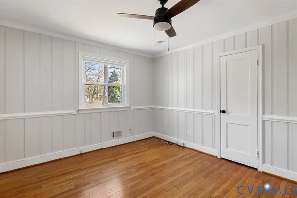 an empty room with wooden floor cabinet and windows