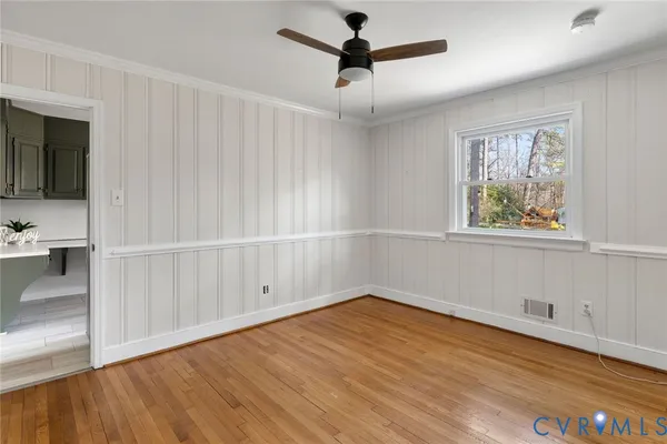 a view of empty room with wooden floor and fan
