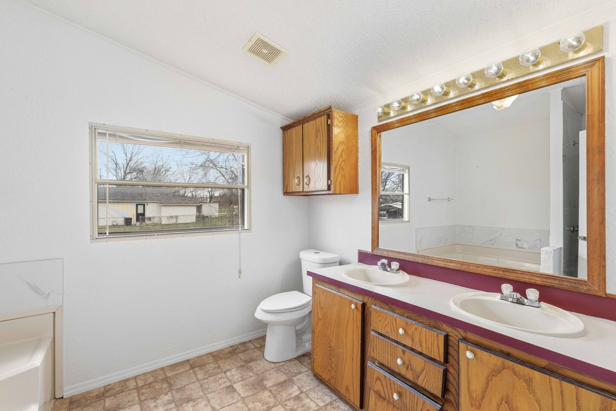 608 4th Street Blanket, TX 76432 - Photo 8 of 24 a bathroom with a granite countertop sink a toilet a mirror and a shower