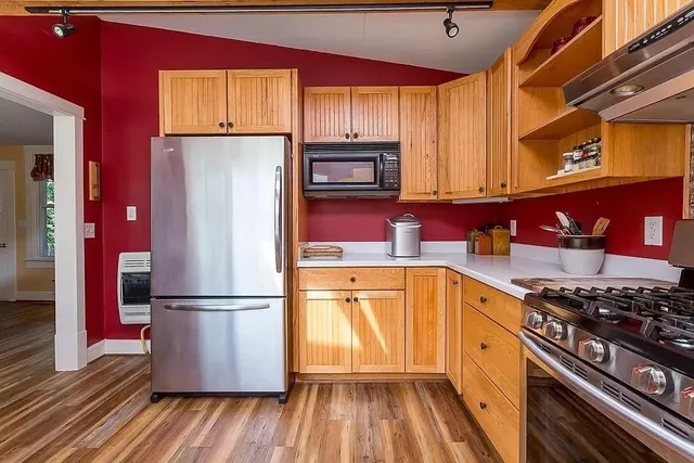 a kitchen with stainless steel appliances granite countertop a refrigerator stove and wooden cabinets