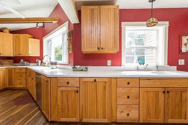 a kitchen with granite countertop a sink and dishwasher wooden cabinets with a large window