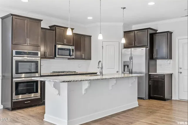 a kitchen with stainless steel appliances granite countertop a sink a stove and a wooden floors